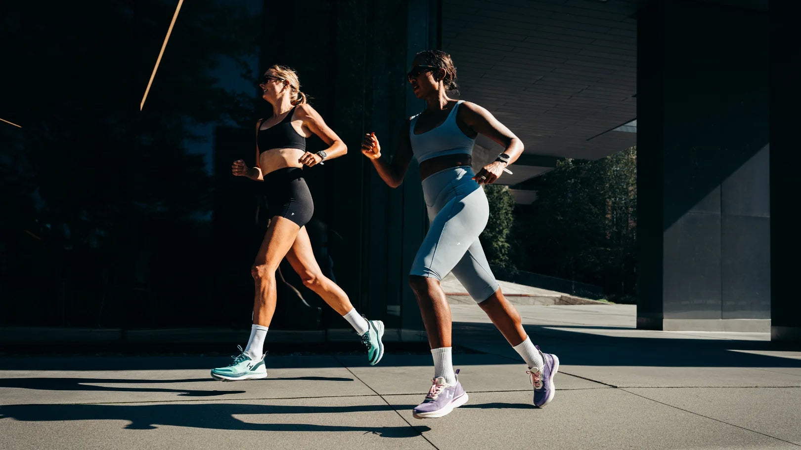 Two runners mid-stride in low light, wearing the Cambie